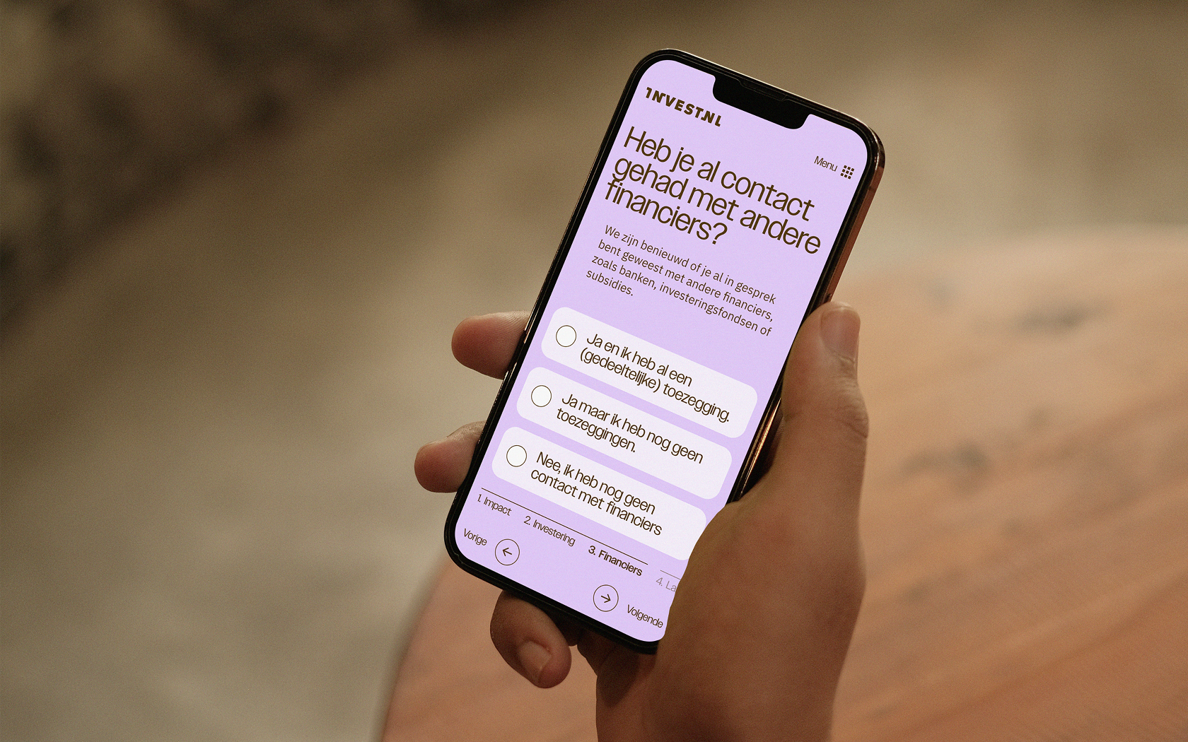 Je ziet een mobiel met daarop de screenshot van de InvestNL-website.
