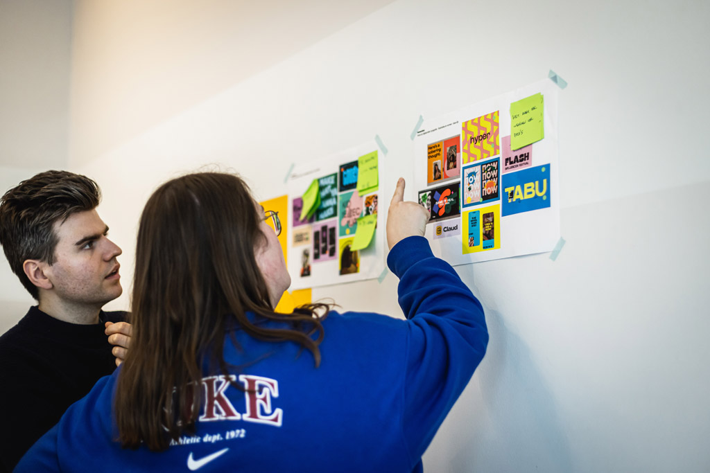 Een designer en ux-designer wijzen naar schetsen op de muur