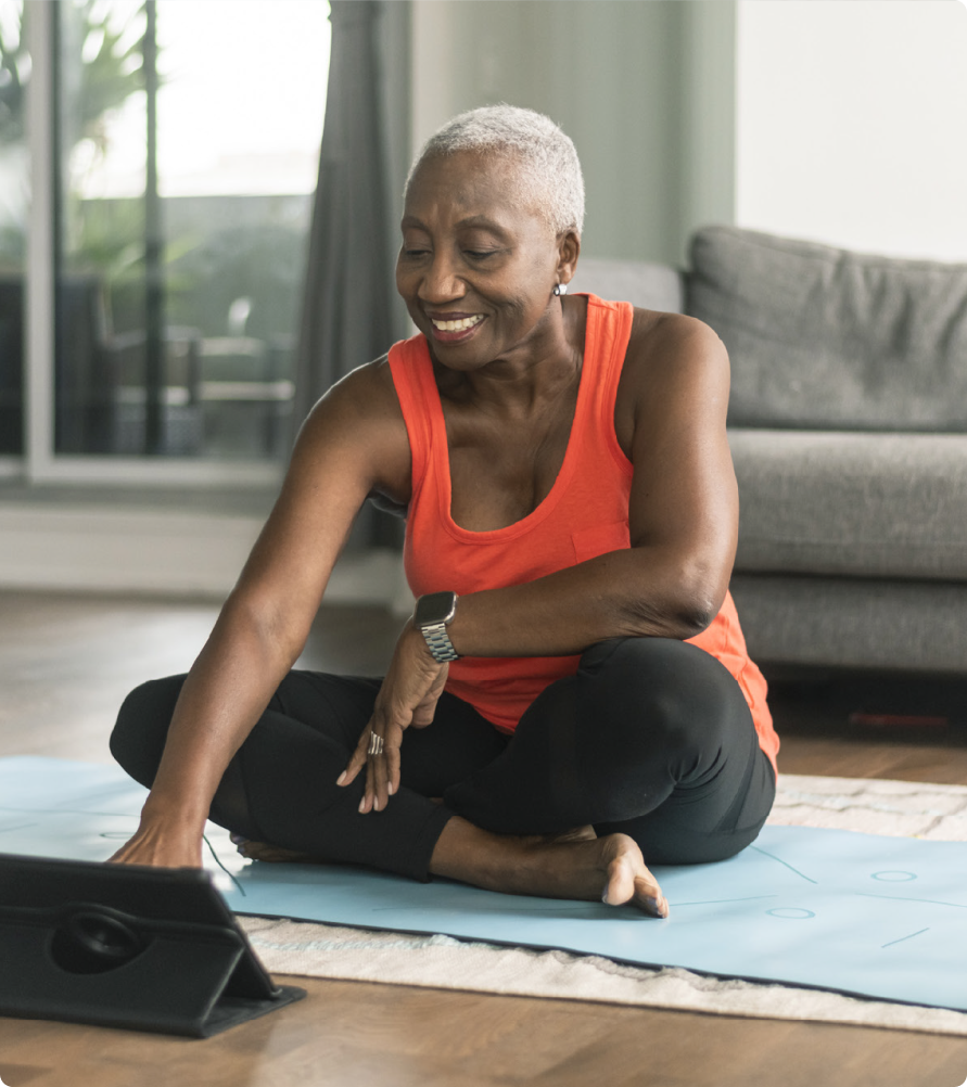 Woman on a yoga mat using a smart tablet.