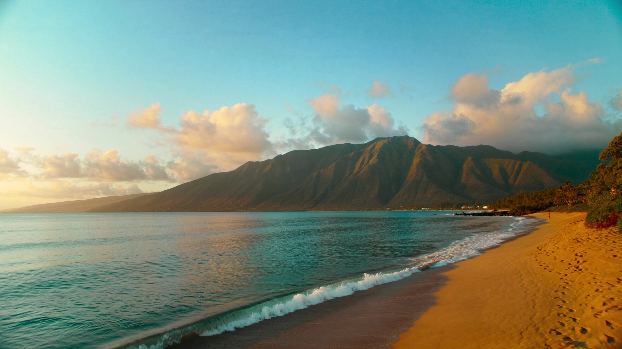 The Kihei shoreline in South Maui looking north across the bay toward the West Maui Mountains at golden hour