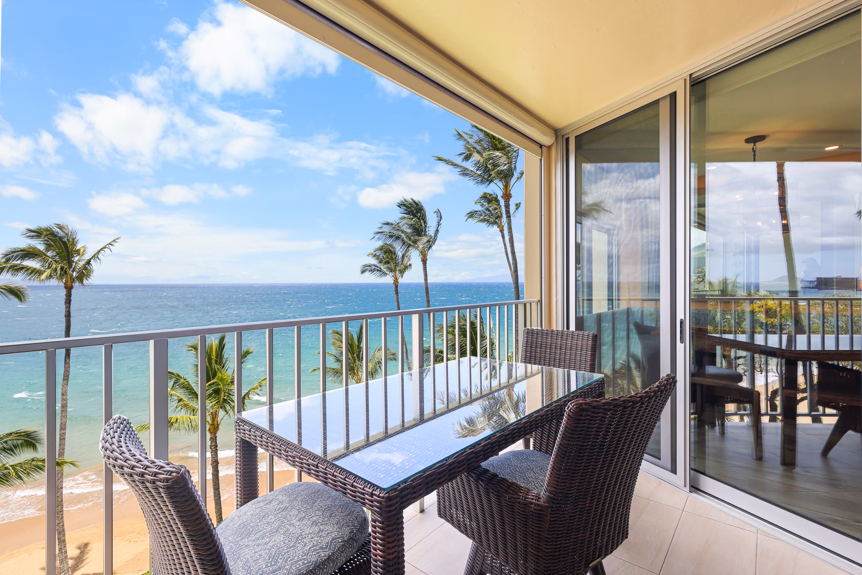 Balcony dining table overlooking palm trees and the ocean.