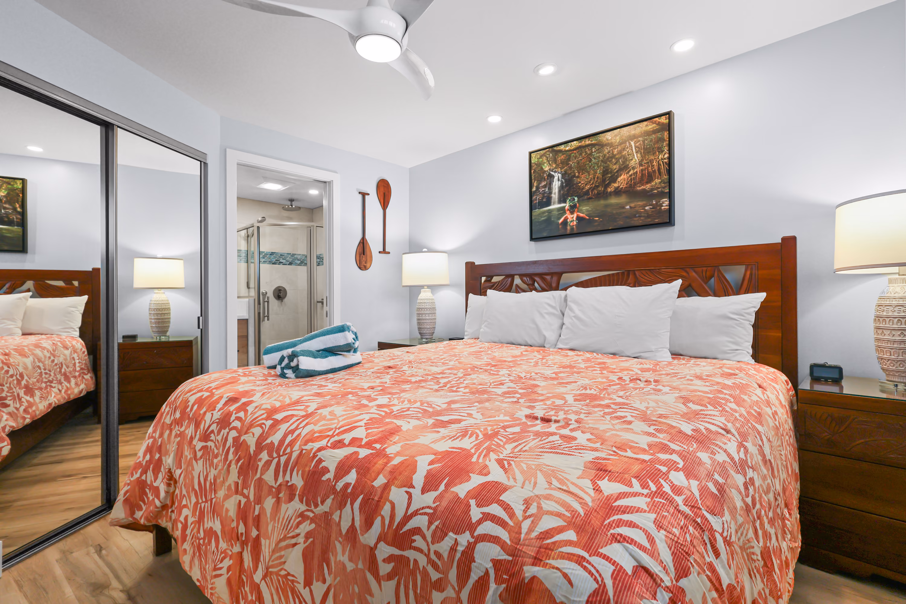 Bedroom with patterned red bedding and mirrored closet doors.