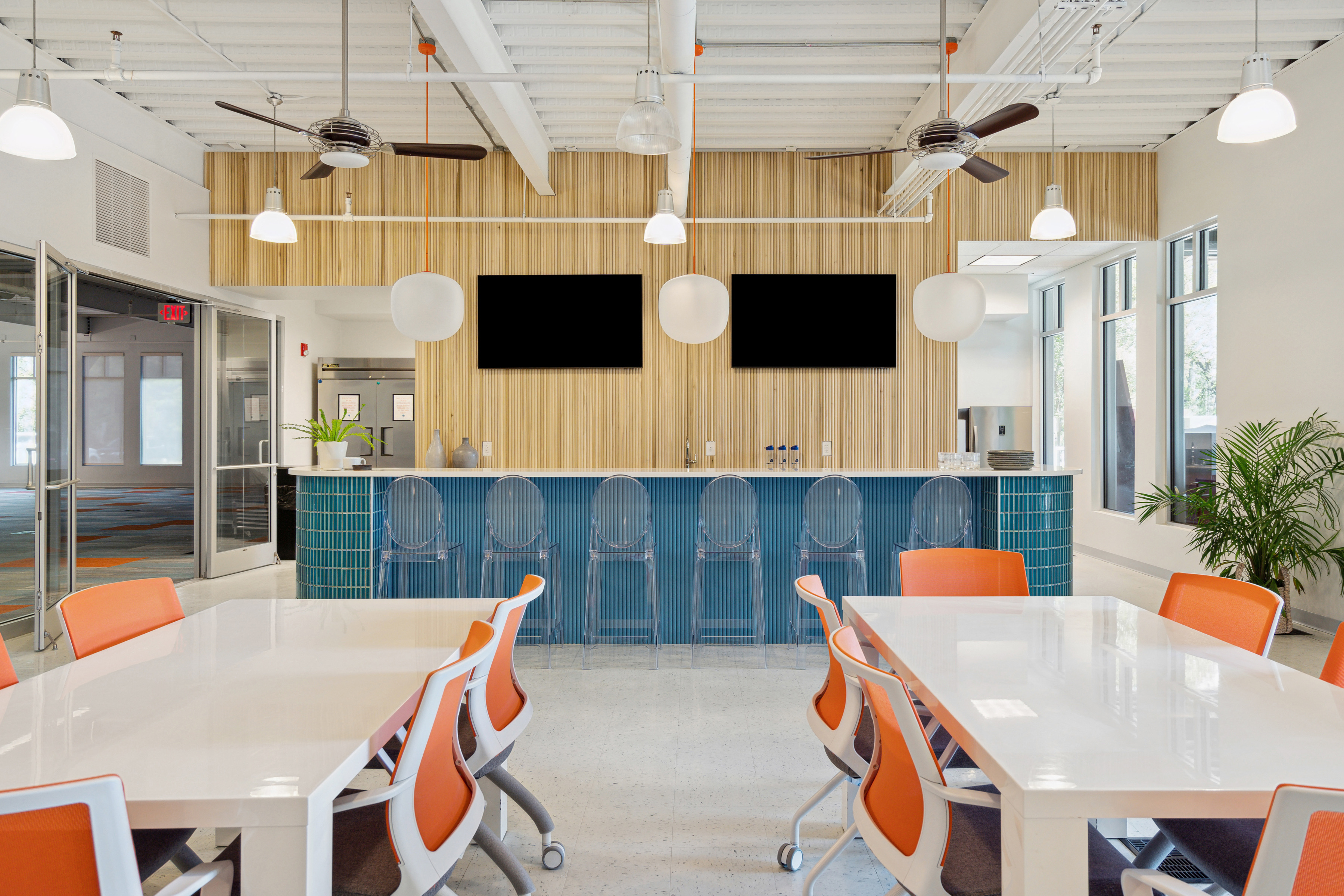 Open concept commercial office space. Custom kitchen with fluted wall, eat-in bar, dining tables, and ping-pong table. Commercial Interior Design by PWD Studio.