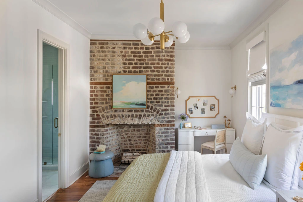 Bright Charleston bedroom featuring French doors, custom drapery, wide-plank hardwood floors, and a pale blue curved dresser. Designed by PWD Studio, the serene retreat blends soft color palettes, natural light, and timeless coastal-inspired design.