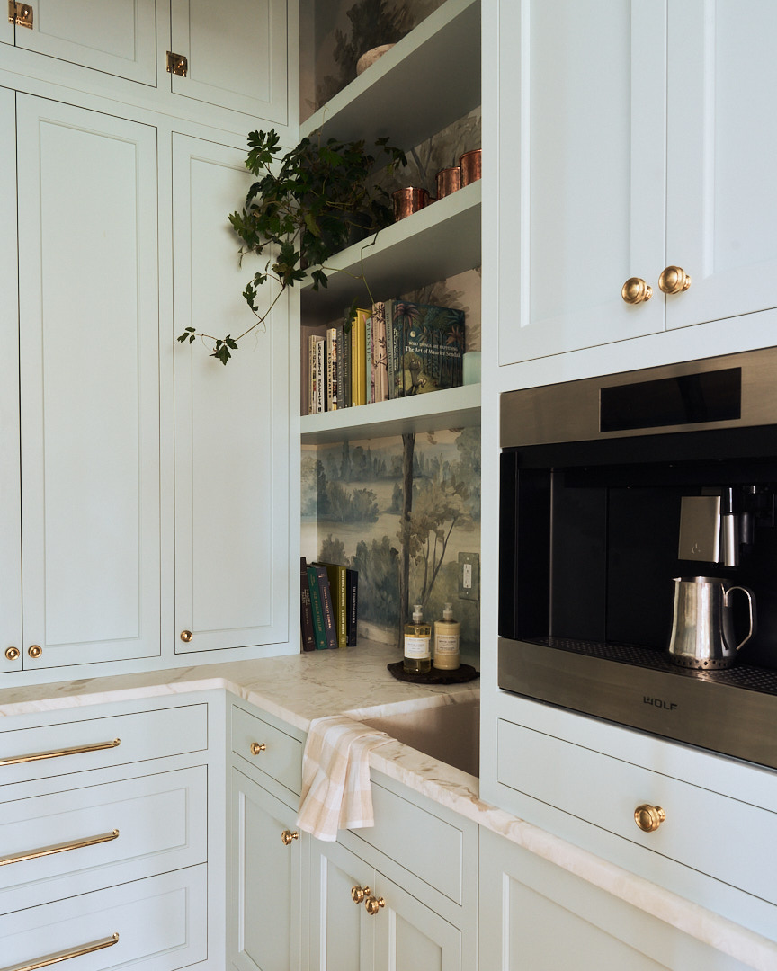 Custom scullery with soft blue cabinetry, marble countertops, built-in coffee station, open shelving, and hand-painted landscape wallcovering in a luxury Kiawah Island residence.