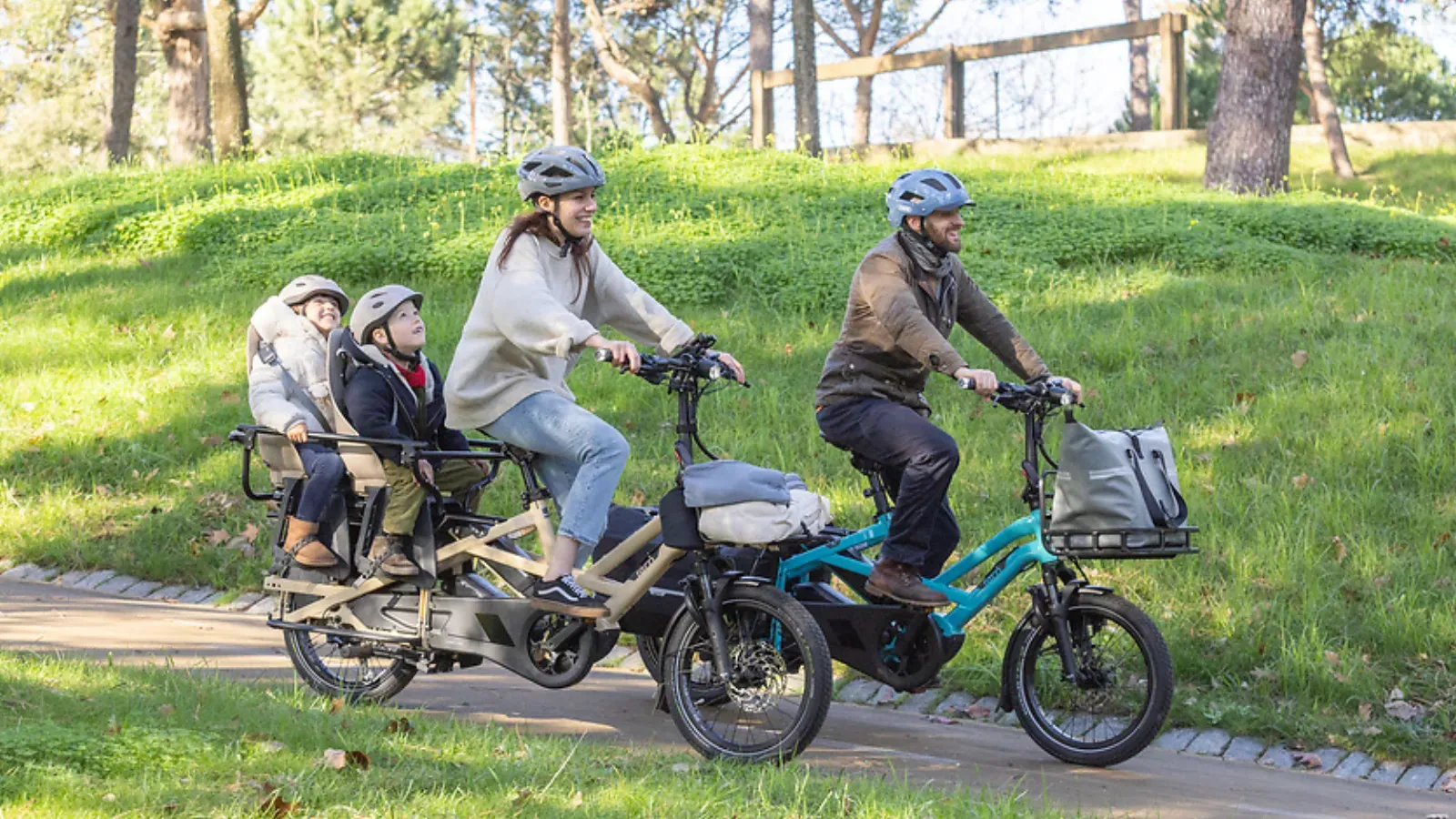 Two Tern cargo bikes with riders and children on a forest path on a sunny day
