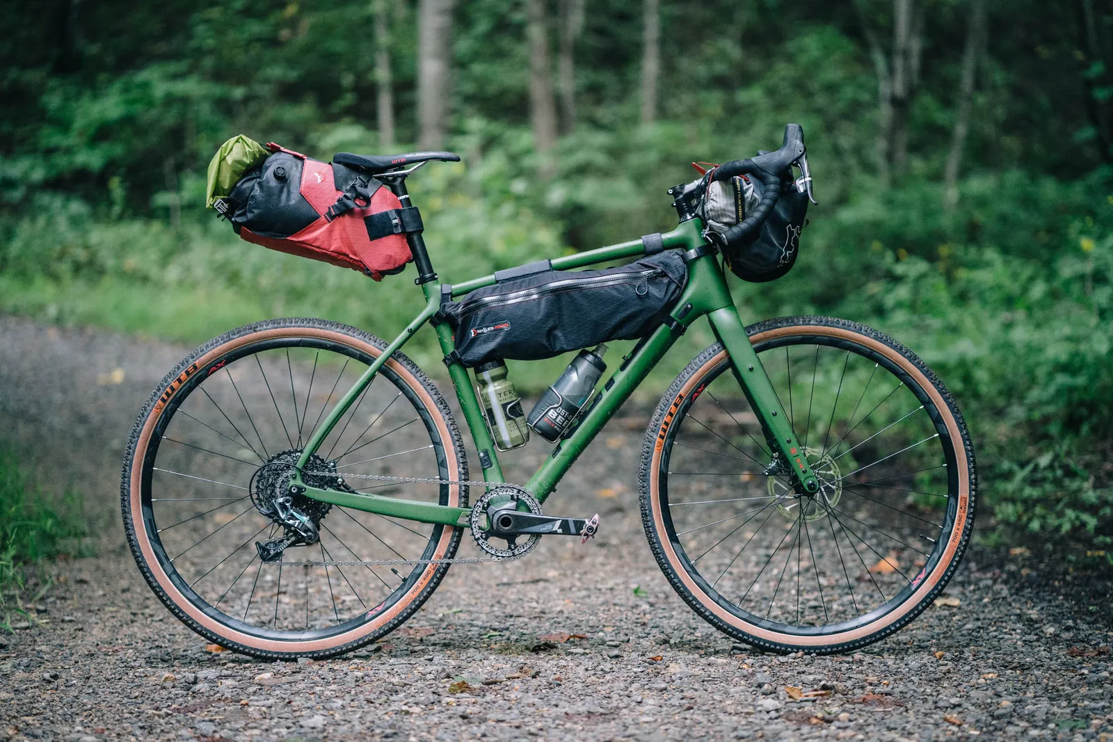 Green Kona mountain bike with panniers on a forest trail