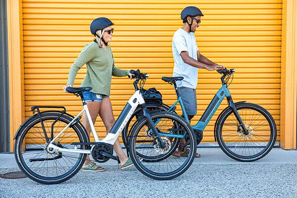 Deux vélos électriques Gazelle, un blanc et un bleu, devant un mur jaune