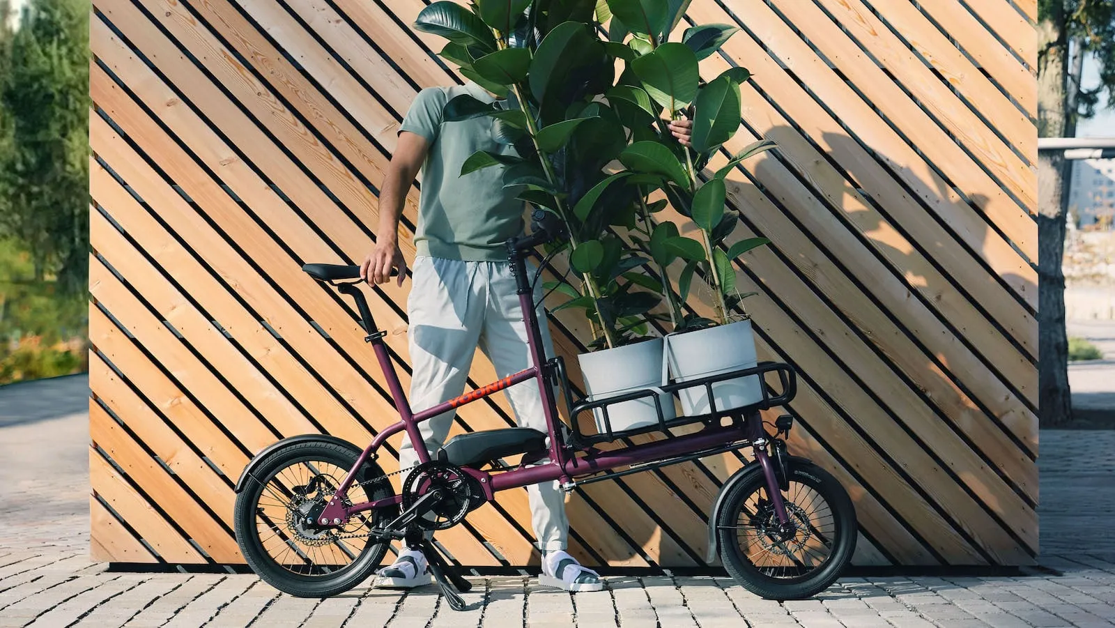 Yoonit Compact Cargo Bike in Purple with a Sturdy Frame in Front of a Diagonal Wooden Panel