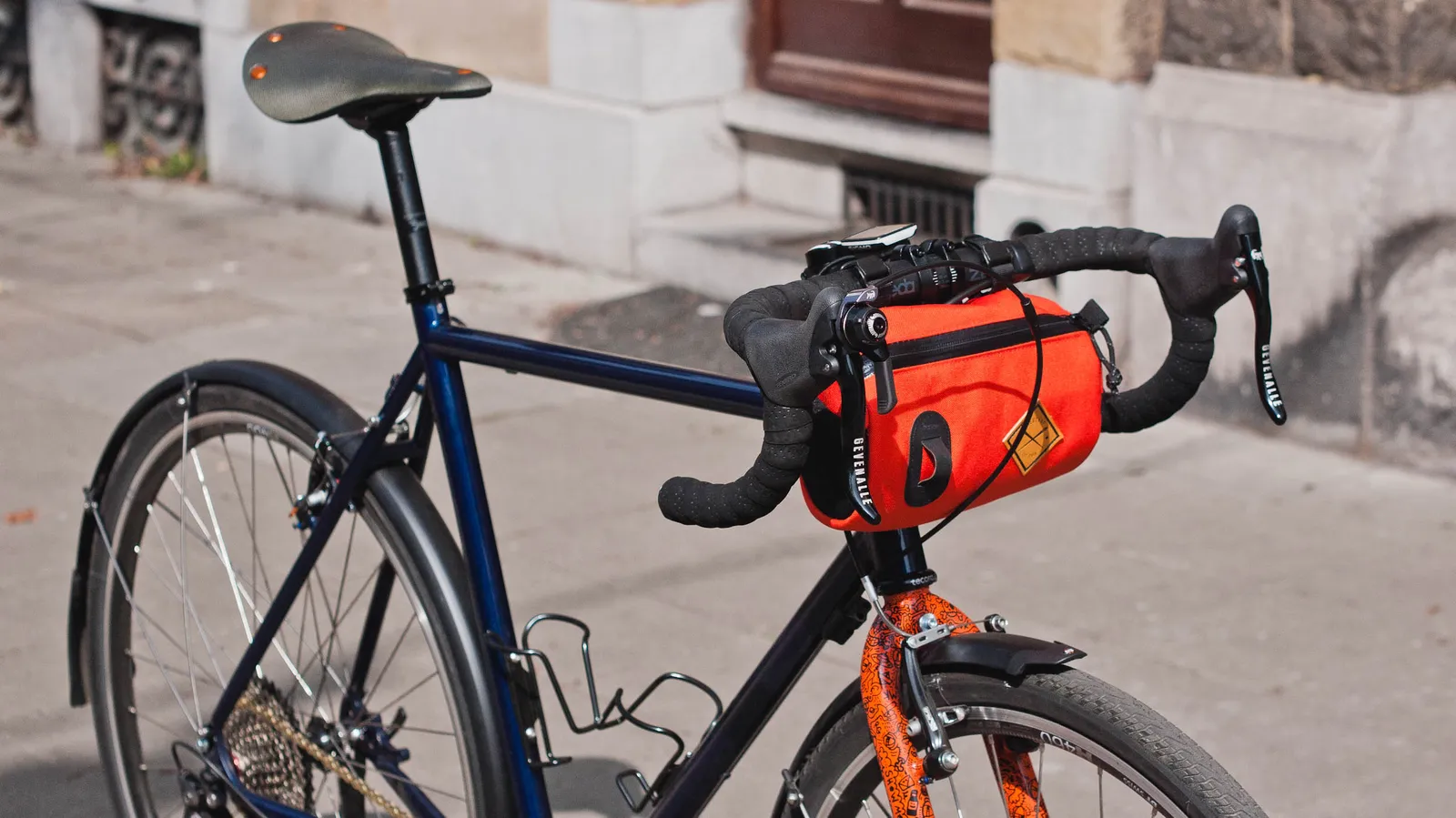Blue Intec bike with a red bag on the handlebars, sturdy frame, cobblestone street in the background