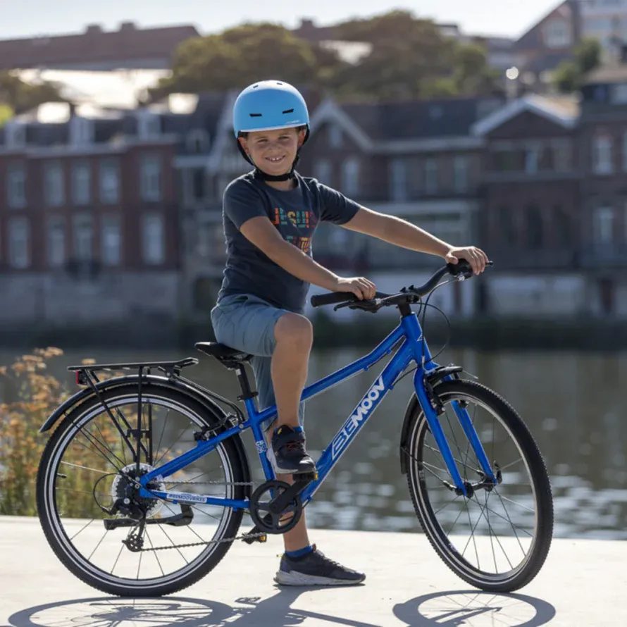 Blue BeMoov children's bike with a lightweight frame, a boy wearing a blue helmet, with a riverbank in the background