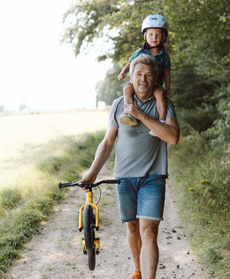 A yellow BeMoov children's bike being ridden by a man on a country path