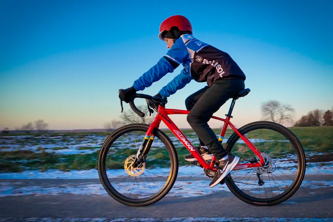 Red BeMoov road bike with a lightweight frame, cyclist in blue clothing, winter landscape in the background