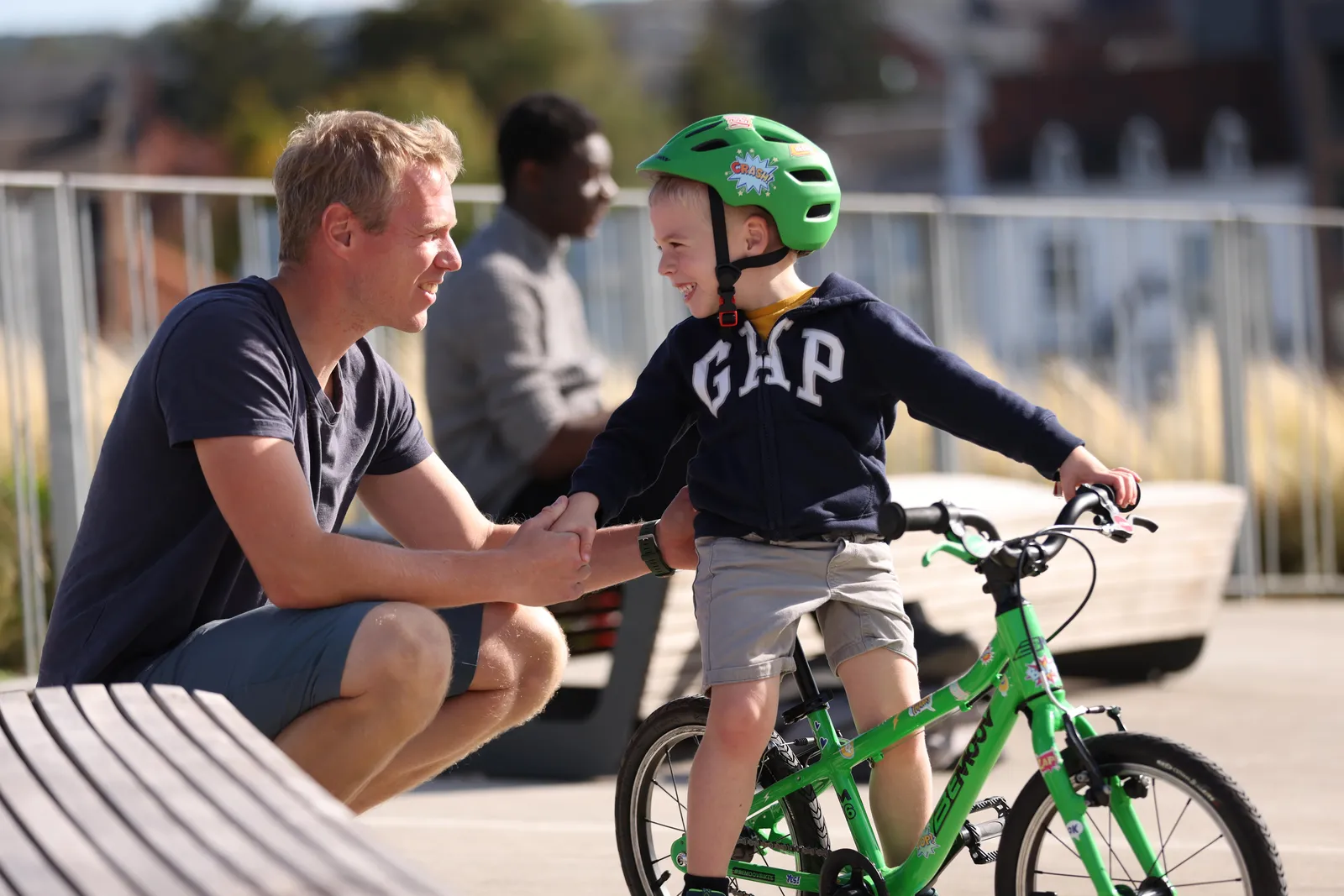 BeMoov green children's bike, lightweight frame, boy wearing a green helmet, sunny outdoors