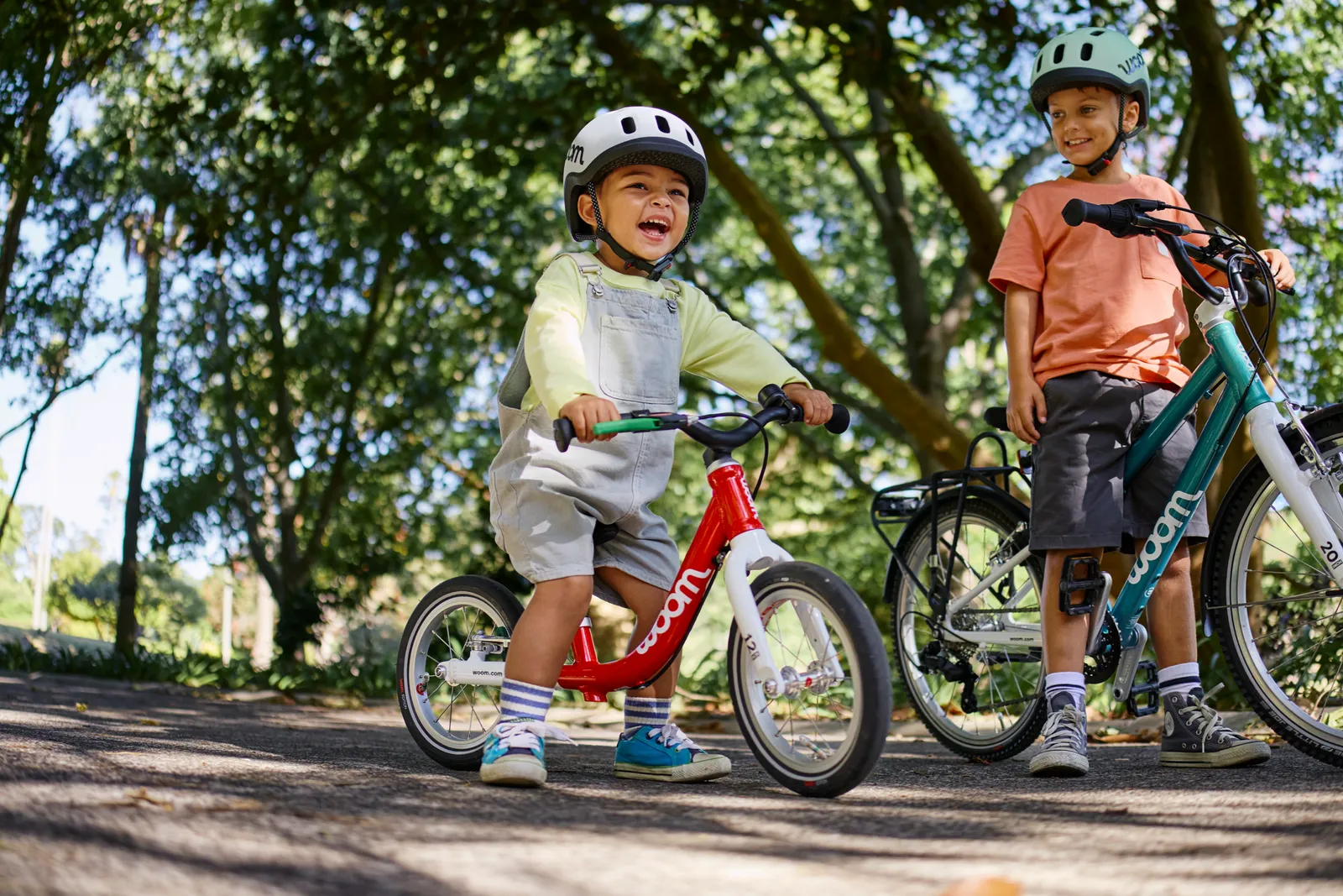 A red Woom children's bike with a low frame in a sunny park