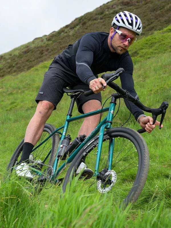Vélo tout-terrain Genesis vert, cadre robuste, cycliste sur sentier herbeux
