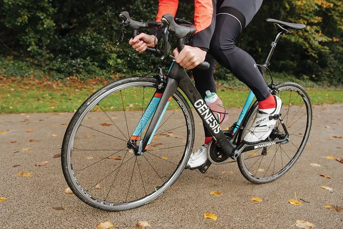 Vélo de route Genesis noir et bleu sur chemin pavé automnal