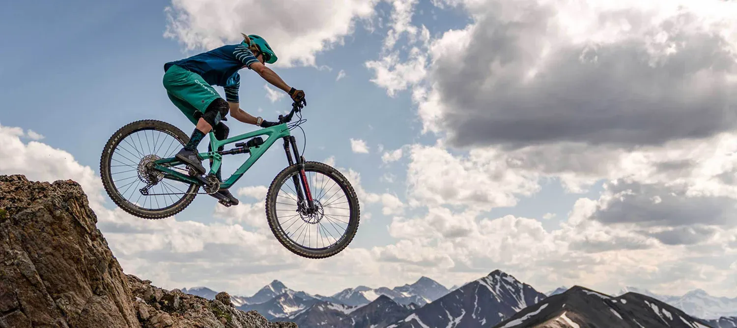 Vélo tout-terrain Salsa turquoise sur montagne rocheuse sous ciel nuageux