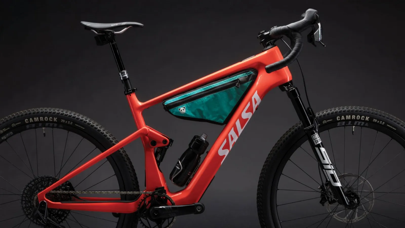 Vélo Salsa rouge avec cadre robuste et sacoche verte sur fond sombre