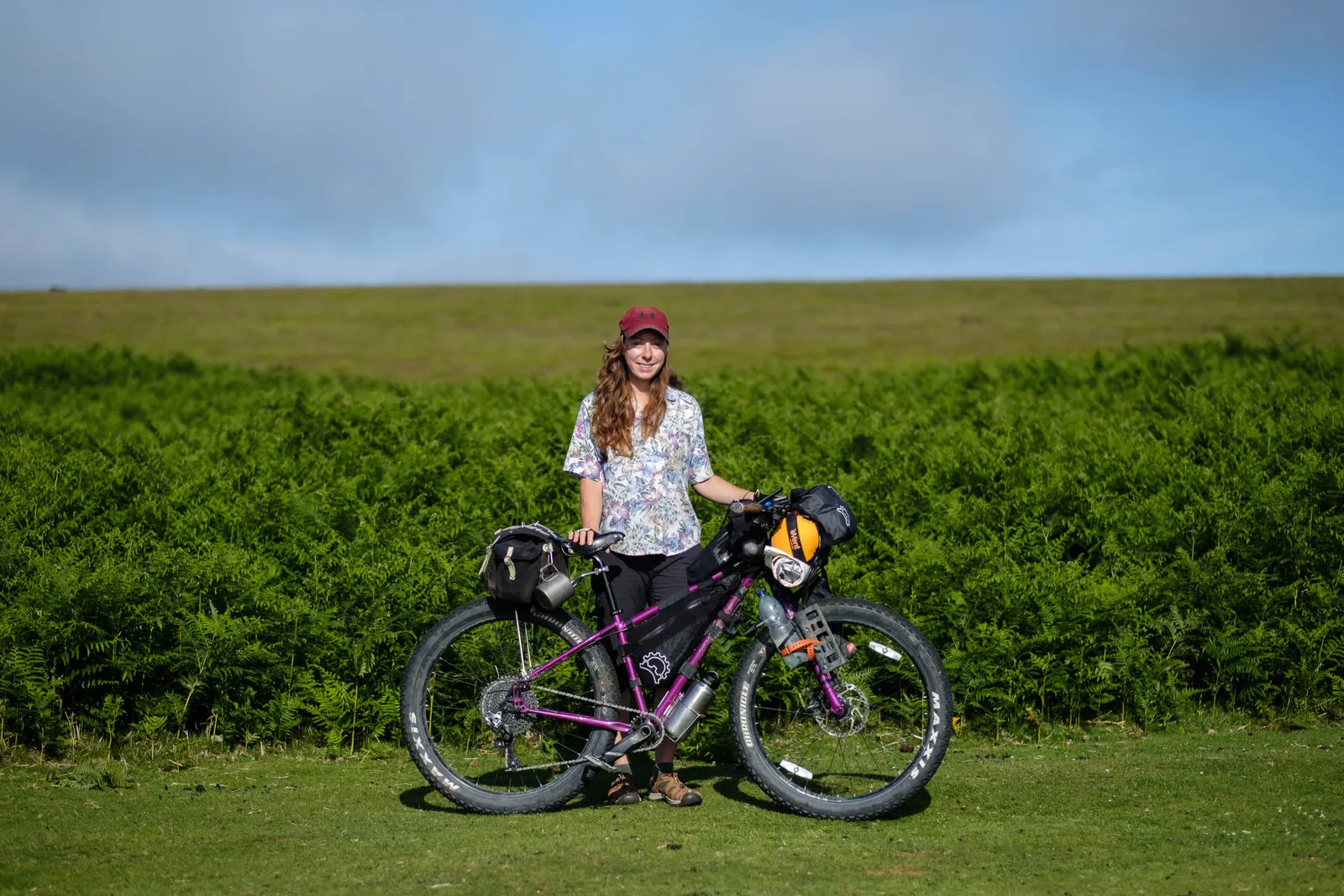 Vélo Salsa violet type aventure sur pelouse verte avec cycliste en fond