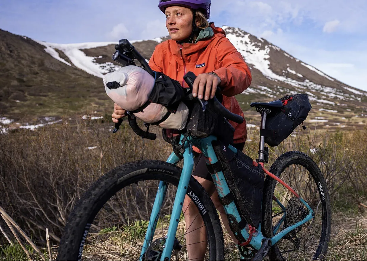Vélo Salsa bleu avec sacoches sur terrain montagneux enneigé