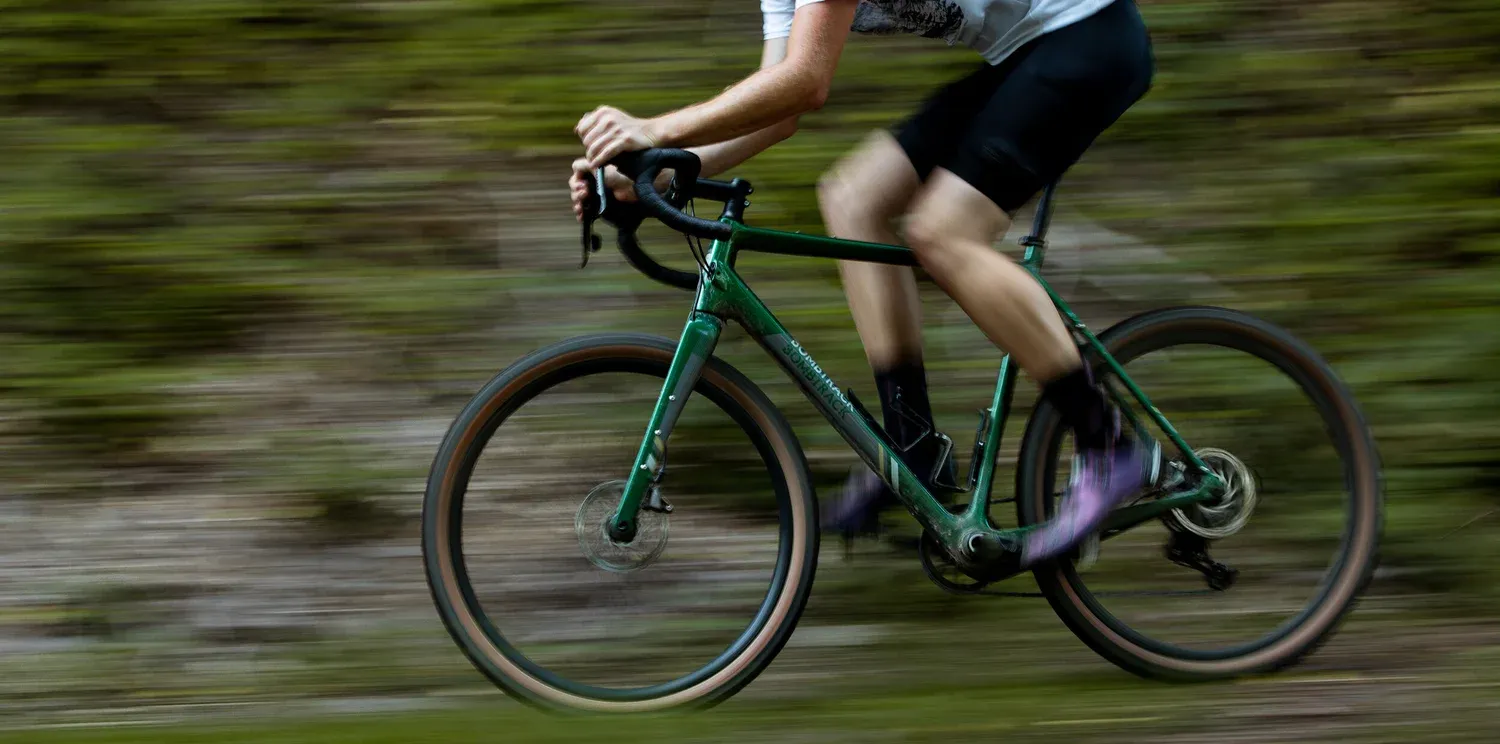 Green Bombtrack road bike in action on a forest trail
