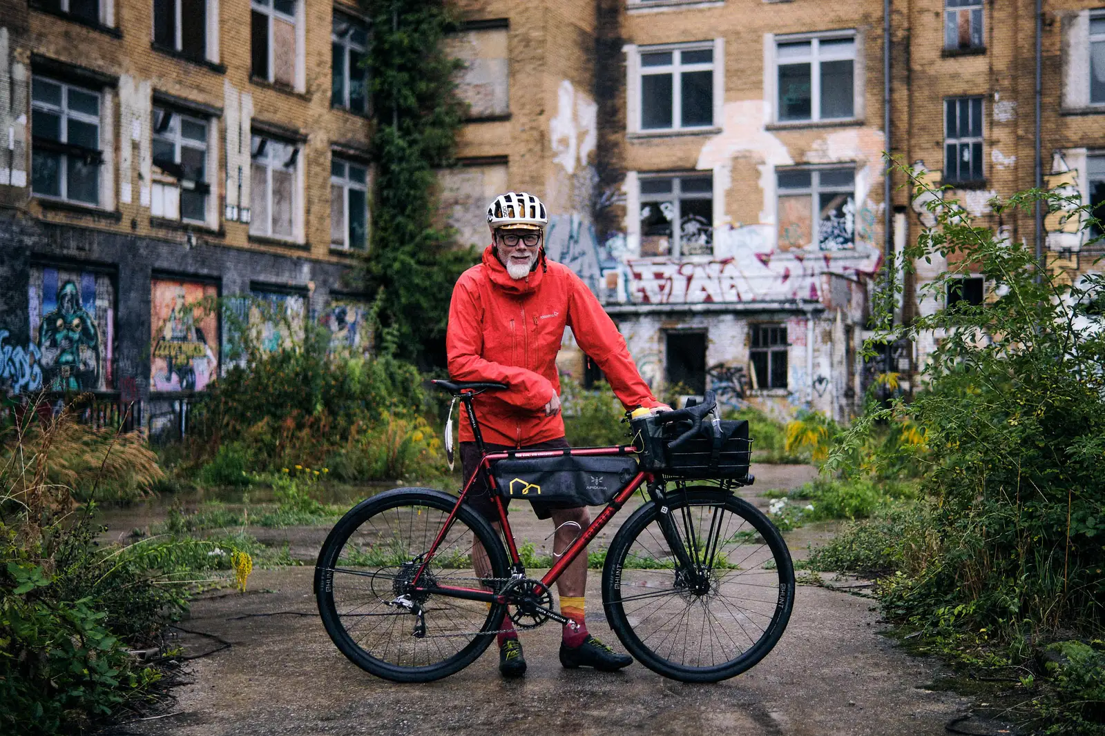 Red Bombtrack bike with a sturdy frame set against a dilapidated urban backdrop