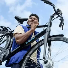Black Batavus bicycle with a straight frame, a man riding it against a blue sky