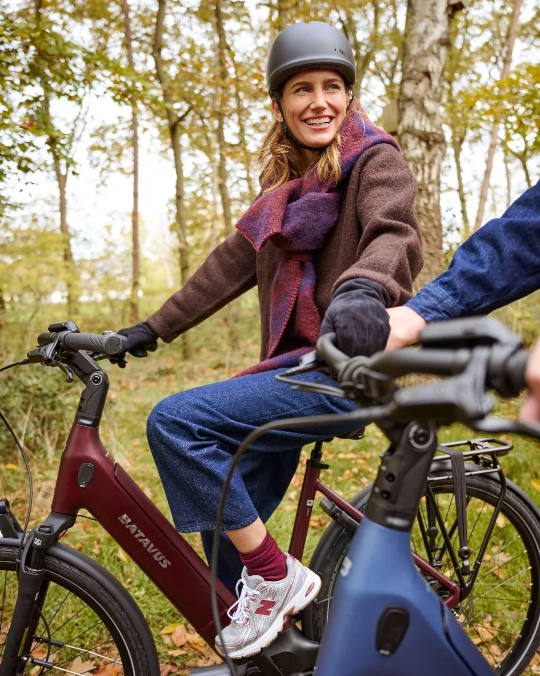 Burgundy-red Batavus e-bike, smiling woman in an autumn forest