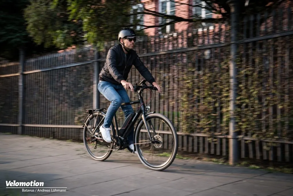Black Batavus city bike with a straight frame, rider wearing a helmet