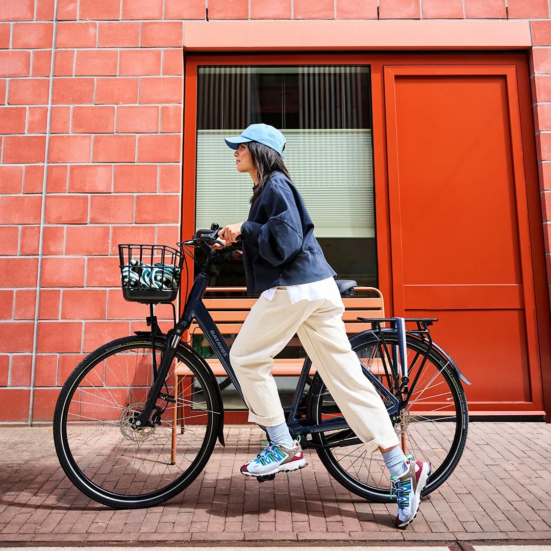 Black Batavus bike with a basket, urban frame in front of a red brick wall