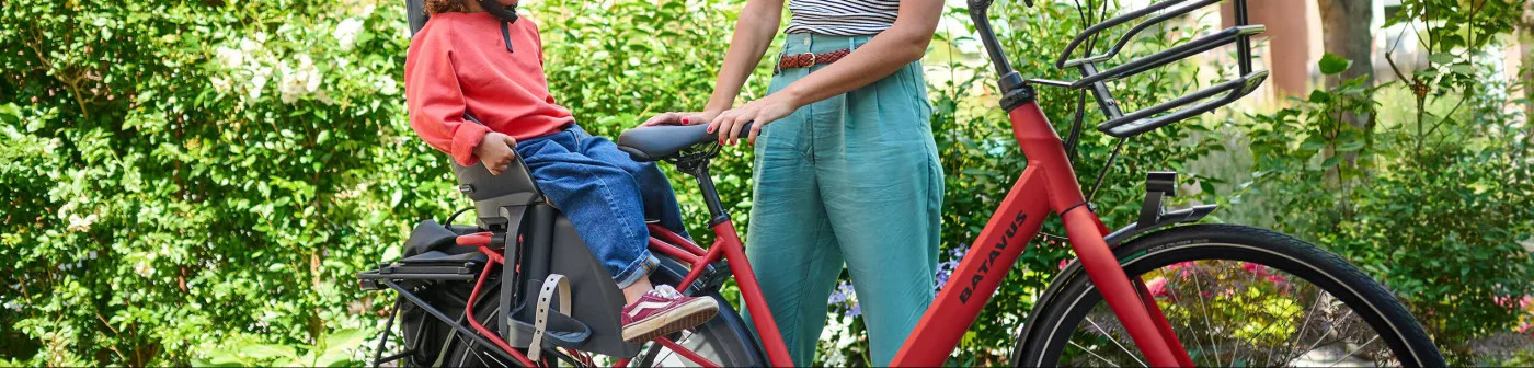 Red Batavus bicycle with a child seat, sturdy frame, and a green landscape in the background