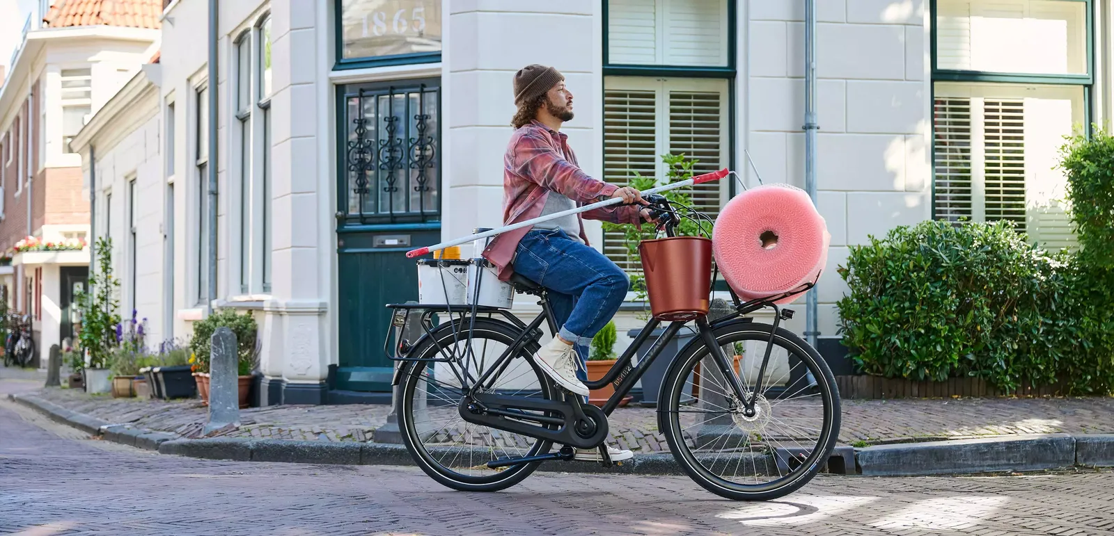 Black Batavus bicycle with a pink front basket in front of an elegant urban building