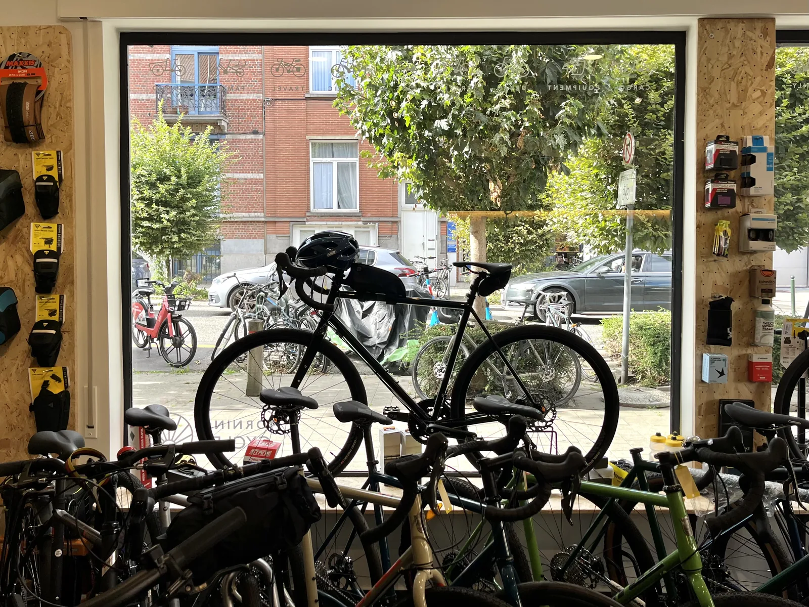 Vélo exposé devant une vitrine, avec d'autres vélos visibles à l'extérieur et des accessoires de vélo en intérieur.