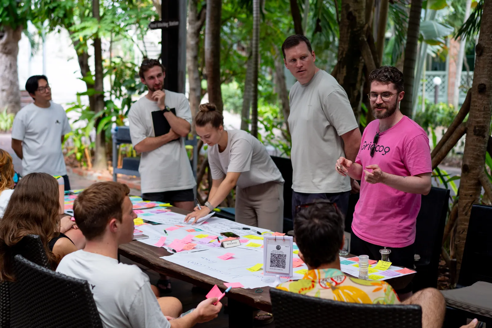 Gridcoggers around a table covered in sticky notes during a retreat workshop