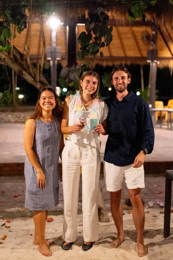 A Gridcogger holding her award between two teammates at the retreat awards night