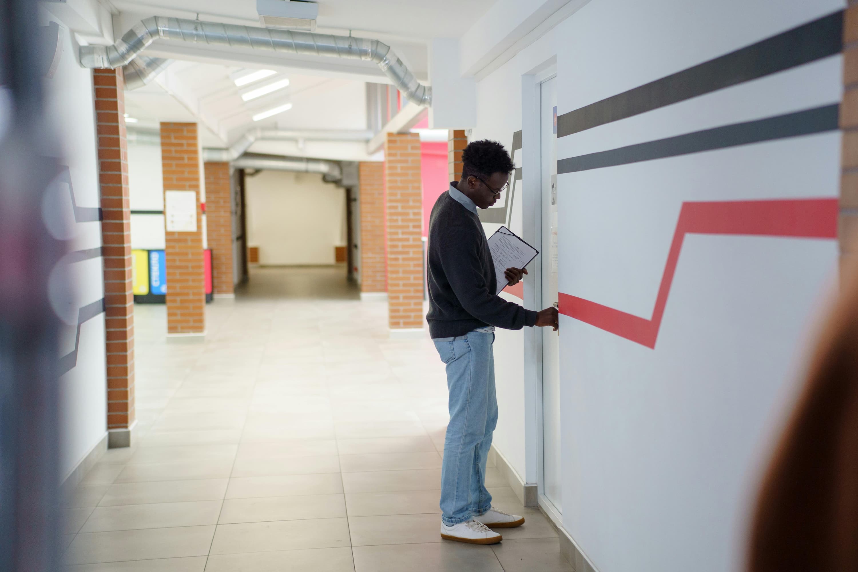 Four students gathered in a school corridor, reviewing documents together and smiling — the collaborative daily life of a school community.