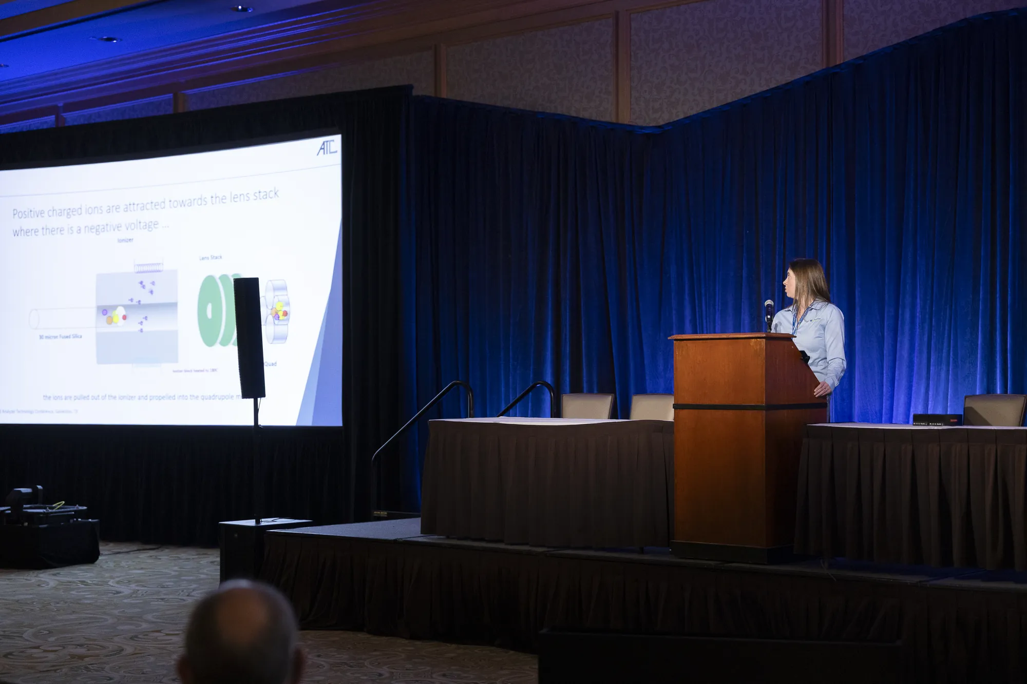 A speaker presenting in front of a large screen