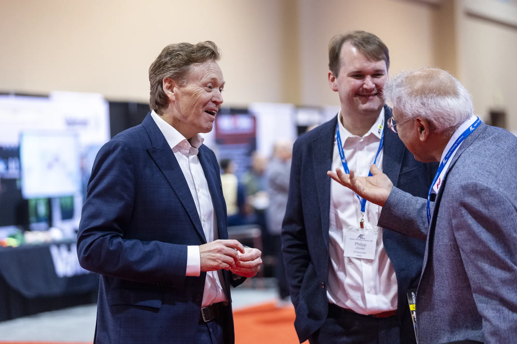 Three attendees laughing together in the exhibit hall
