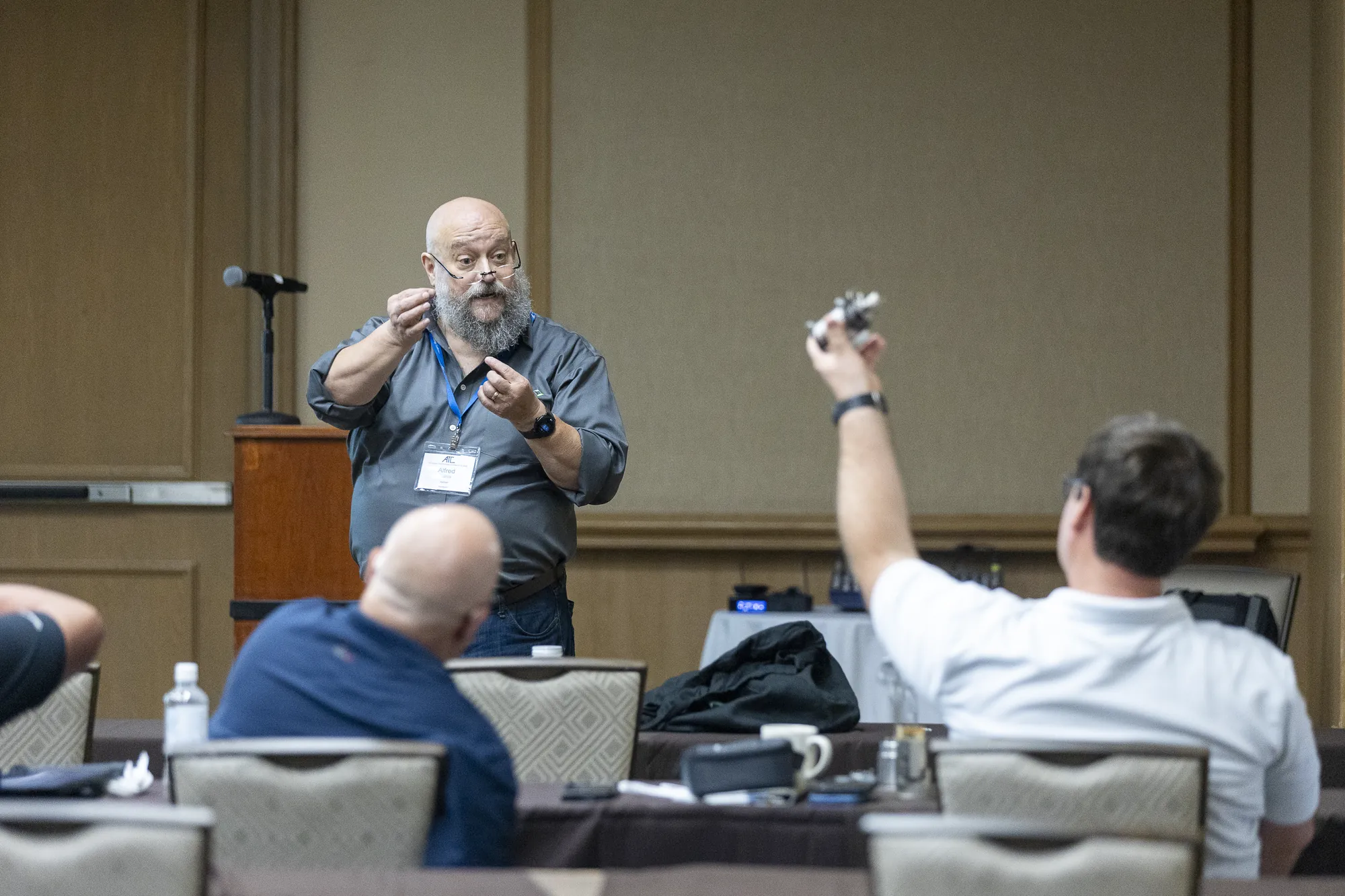 An instructor holding up a device as a student asks a question