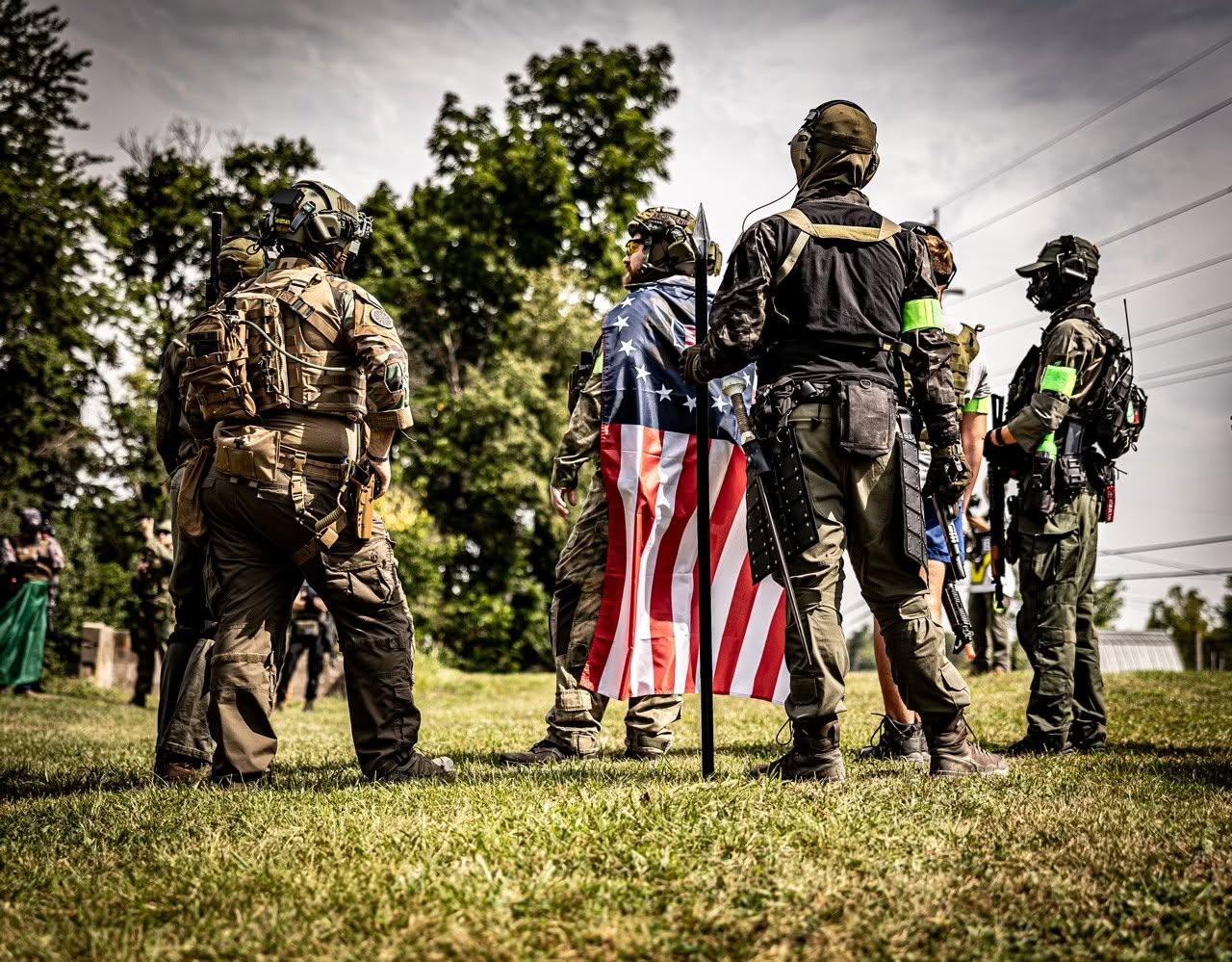 Coyote Force players in tactical gear with an American flag at a field event
