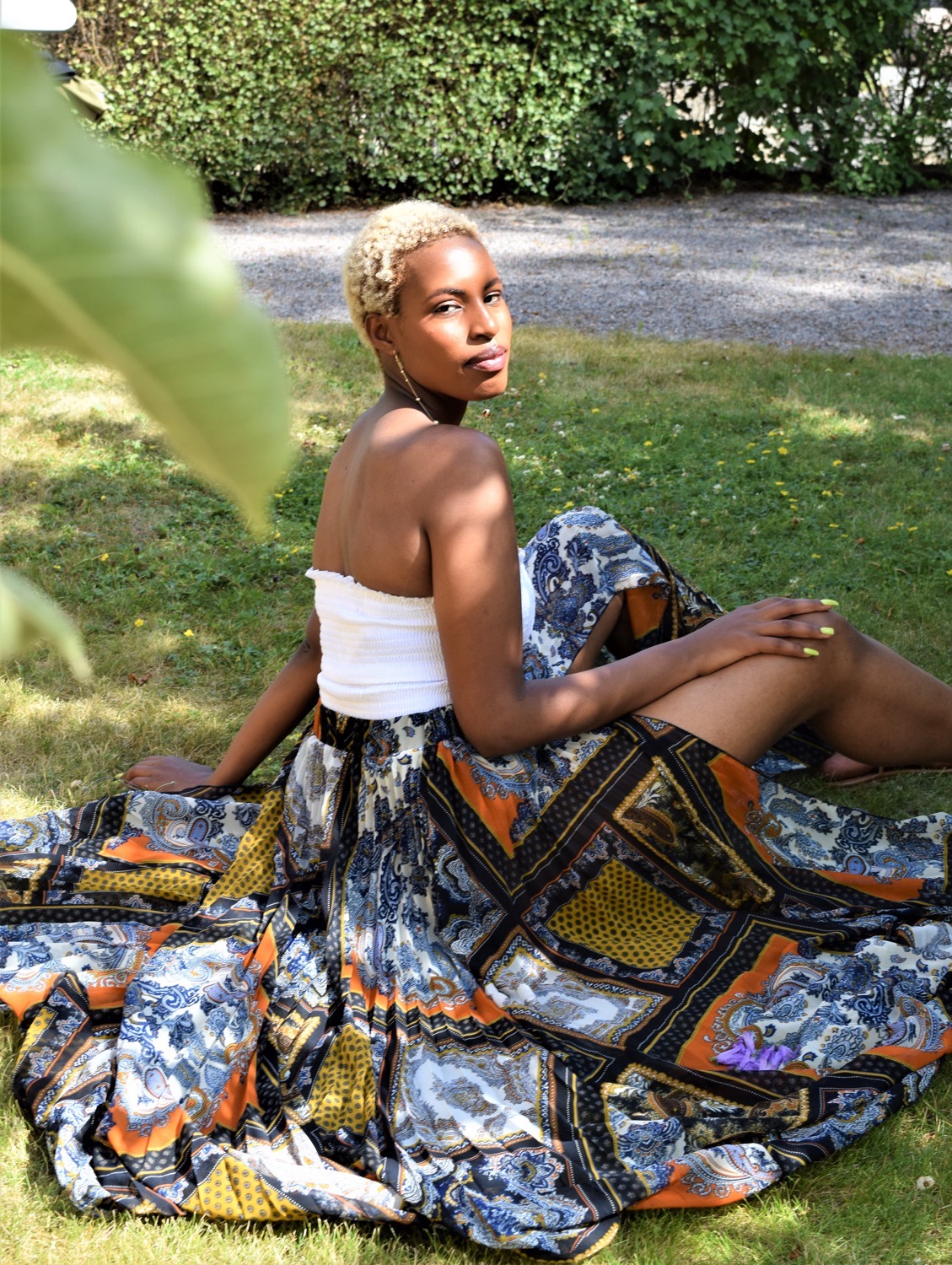 A girl sitting on the grass while posing for the camera.