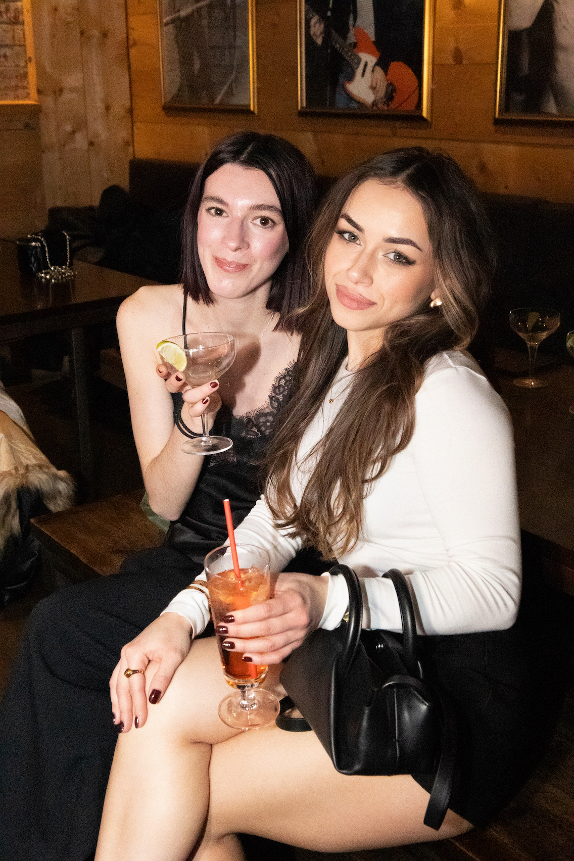 Two girls sitting next to the other and posing for the camera.