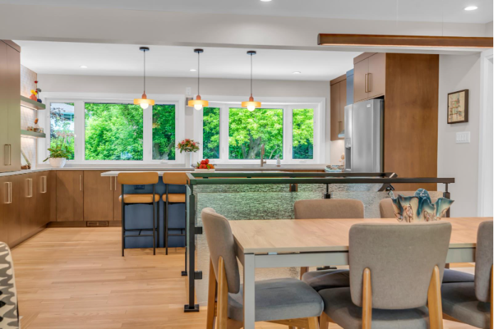 open-concept layout with warm wood cabinetry, large island seating, panoramic windows, and mid-century pendant lights ‍