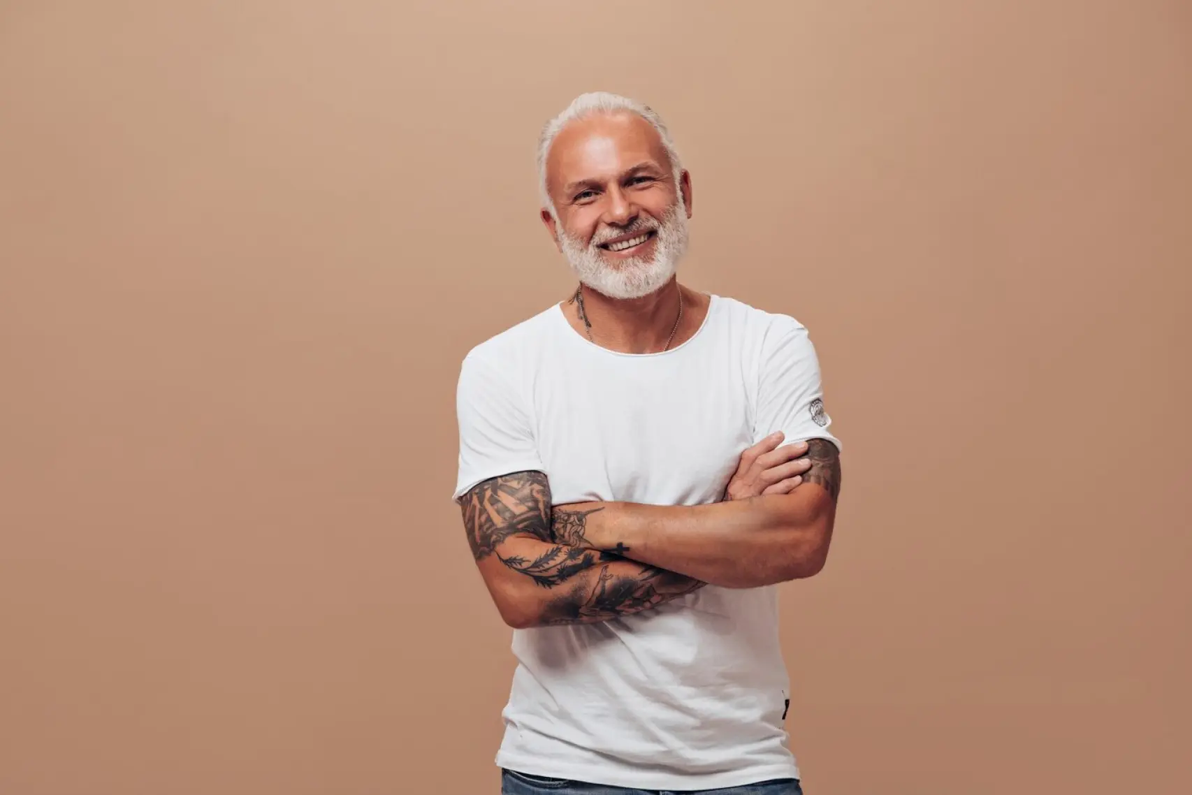 An old man with white beard smiling in a bege background