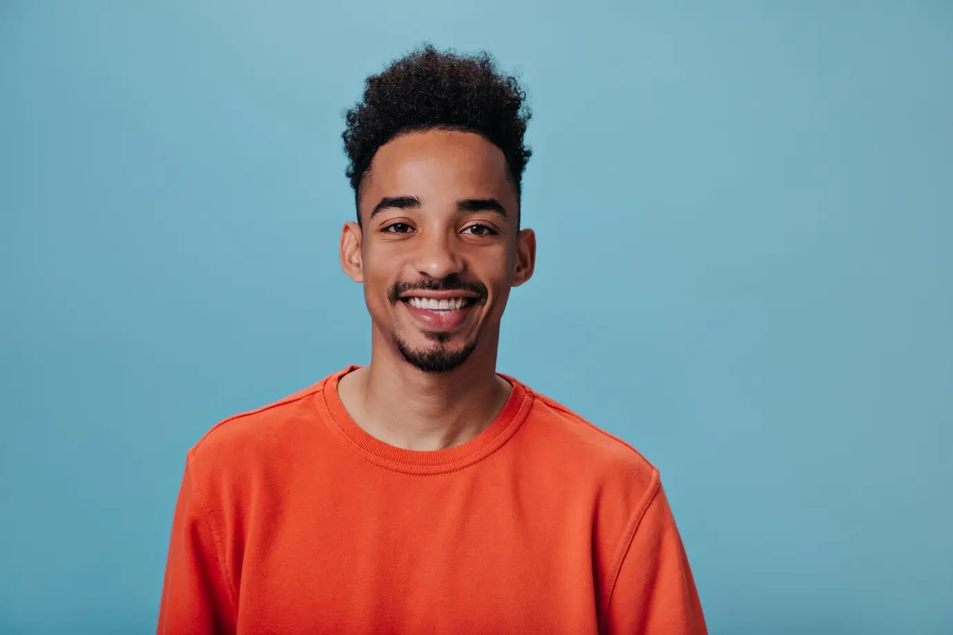 Black man with beard smiling in a blue background