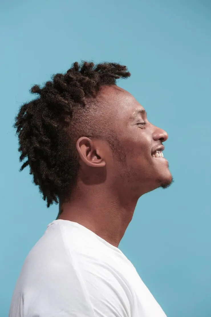 side face of a black man smiling in a light blue background