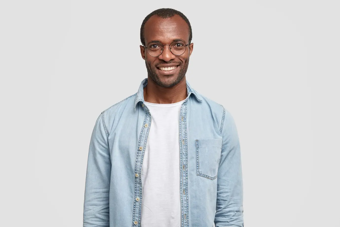 A black man with glasses in a light background