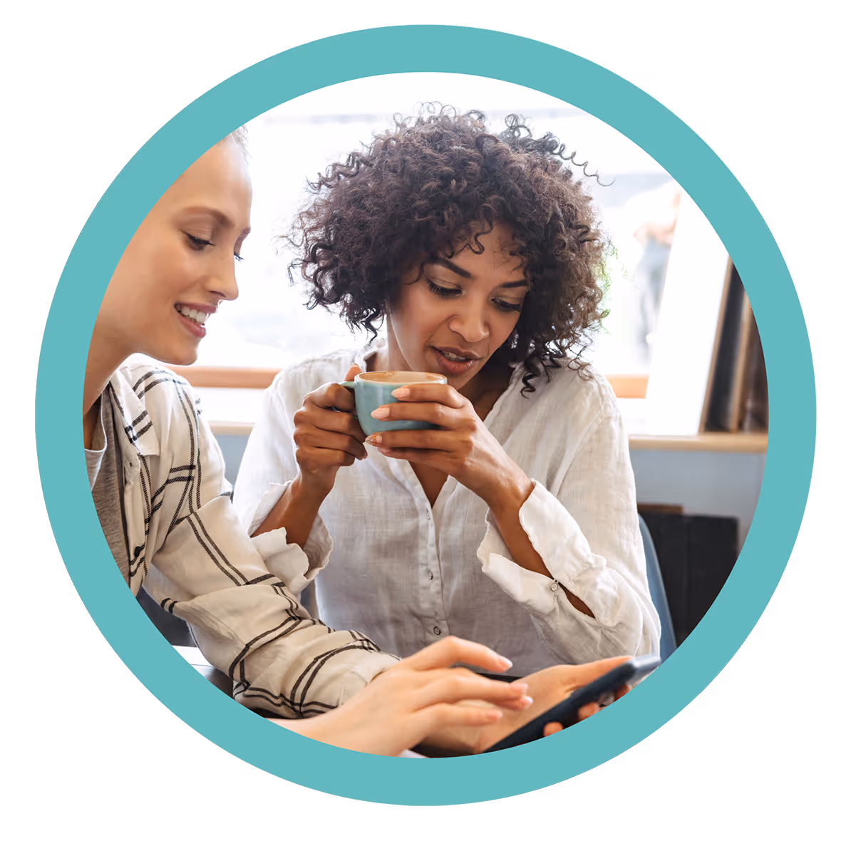 Two women sitting together, one smiling and the other drinking coffee while looking at a phone.