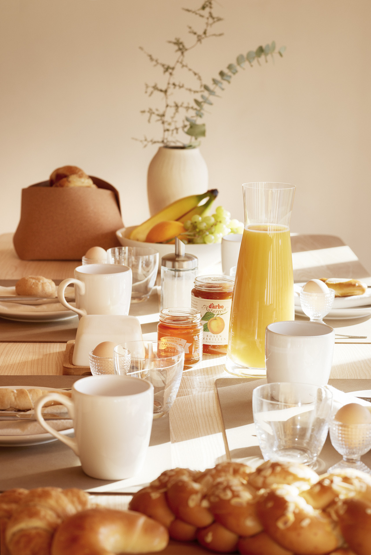 Voll gedeckter Frühstückstisch mit frischem Gebäck, Marmelade, Orangensaft und Kaffee